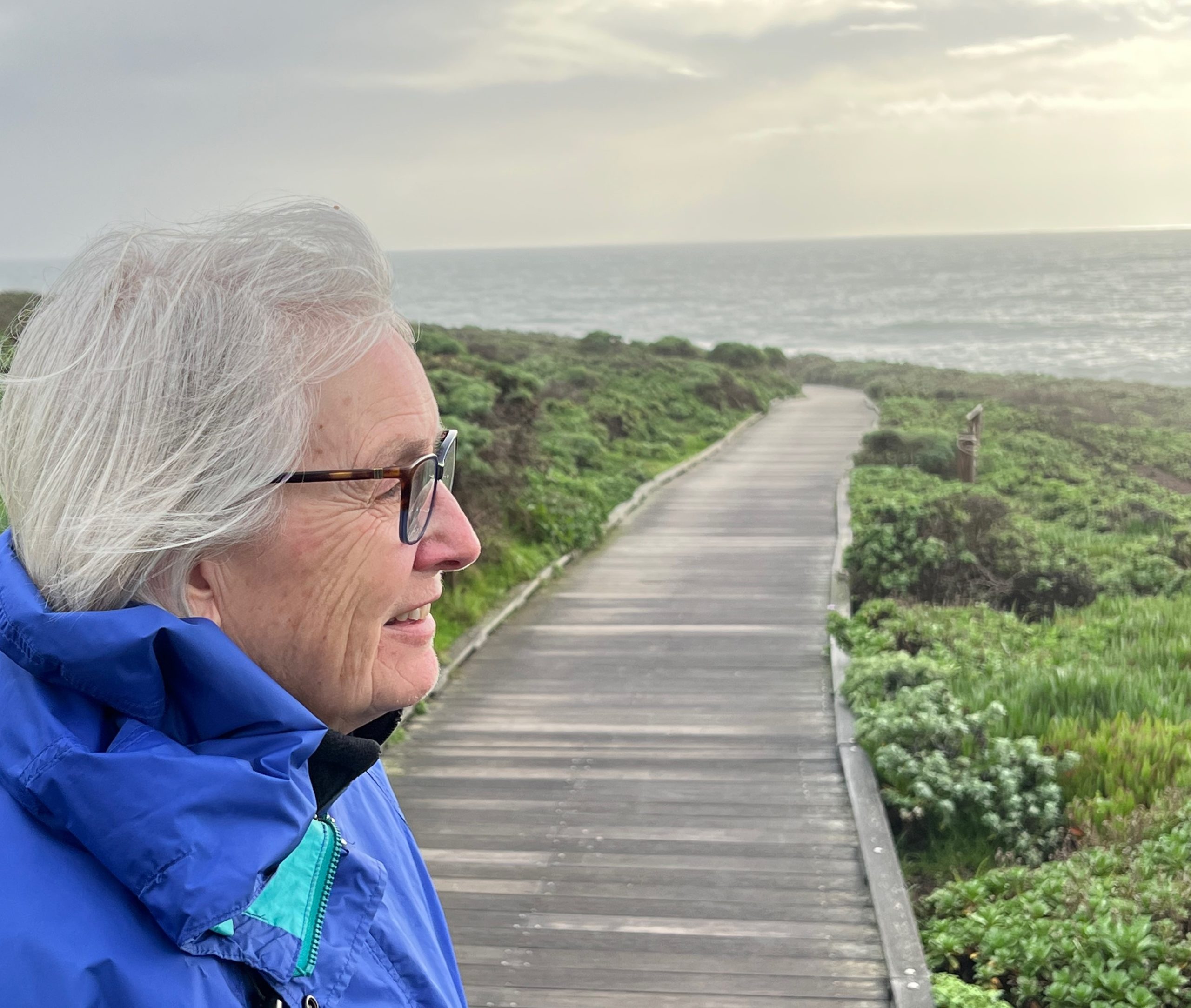 Betsy Hartmann in left forground looking out at lush greenery and a body of water